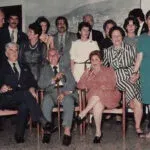 A group of thirteen adults, both men and women, are posing for a formal photograph.